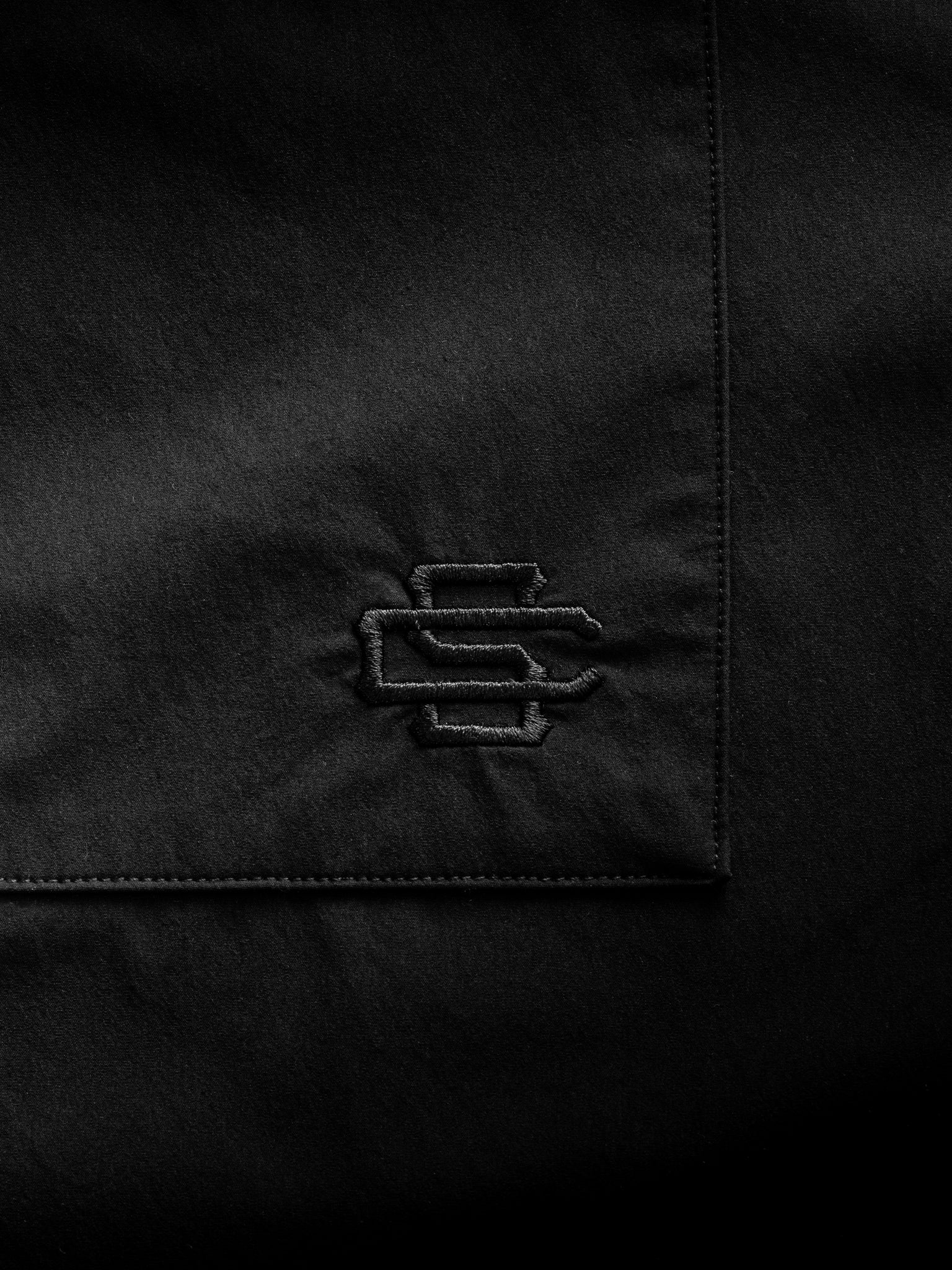 Black SIGNATURE BUTTON UP shirt from Sweats UK displayed flat with collar, buttons, and long sleeves visible.