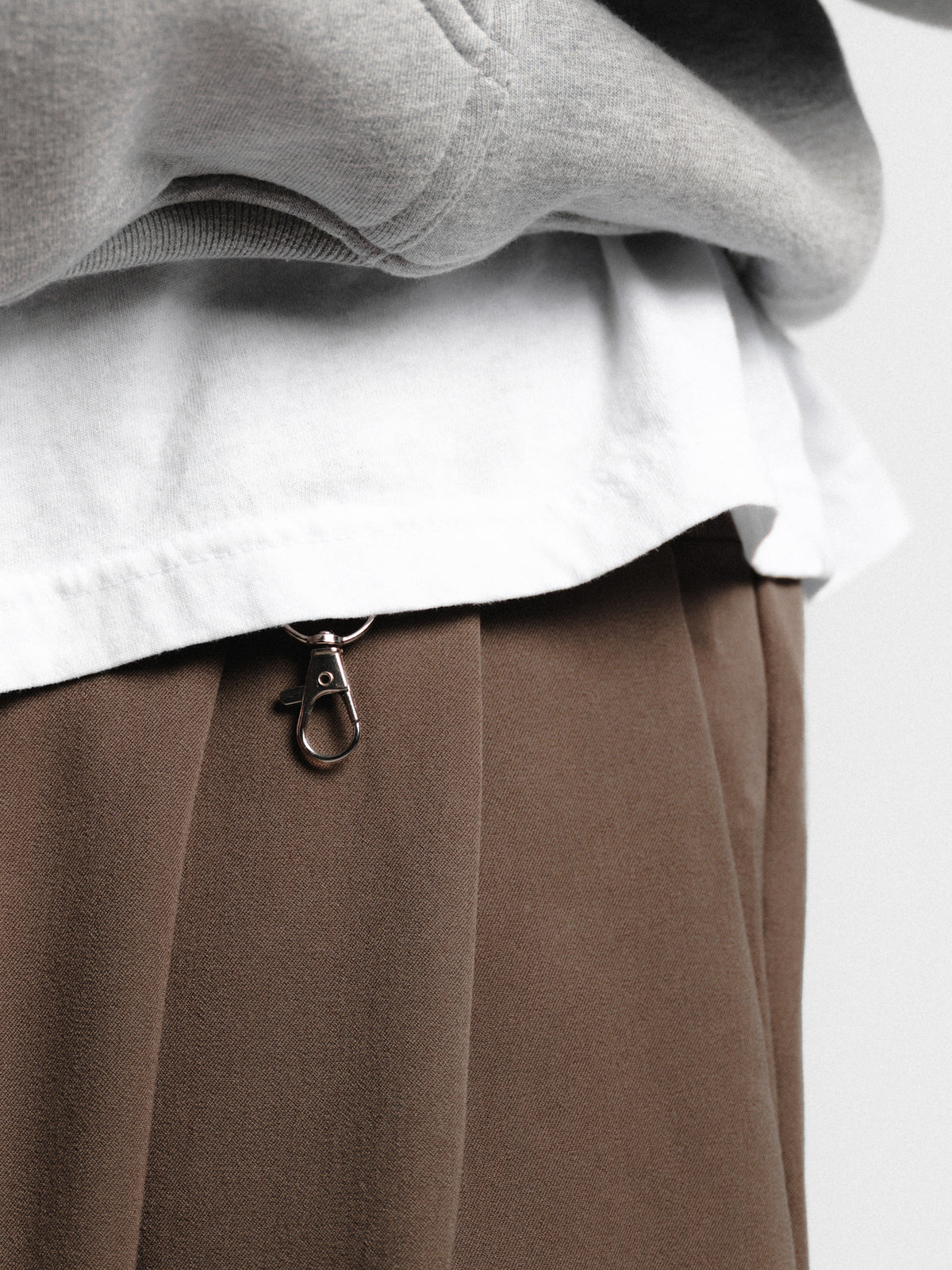 Pair of brown pleated pants by Sweats UK with a tailored fit and crisp pleats, perfect for casual or smart-casual outfits.