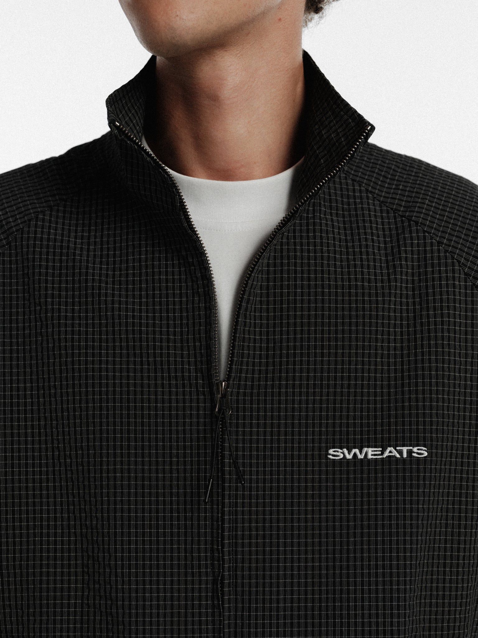 Black and white checkered track jacket from Sweats UK, featuring a stylish athletic design with zip front and ribbed cuffs.