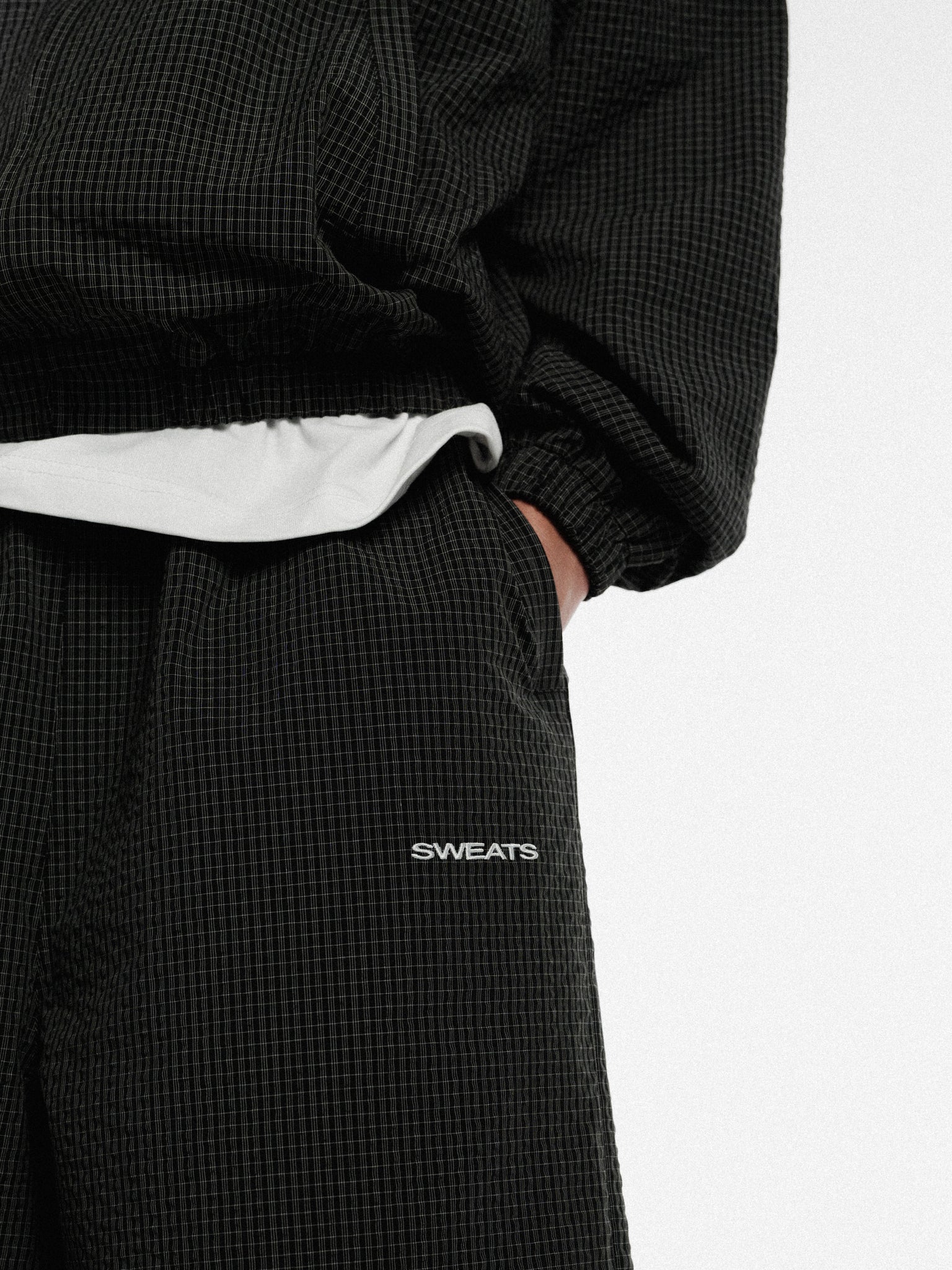 Black and white checkered track shorts by Sweats UK, featuring a comfortable fit and sporty design for active wear.