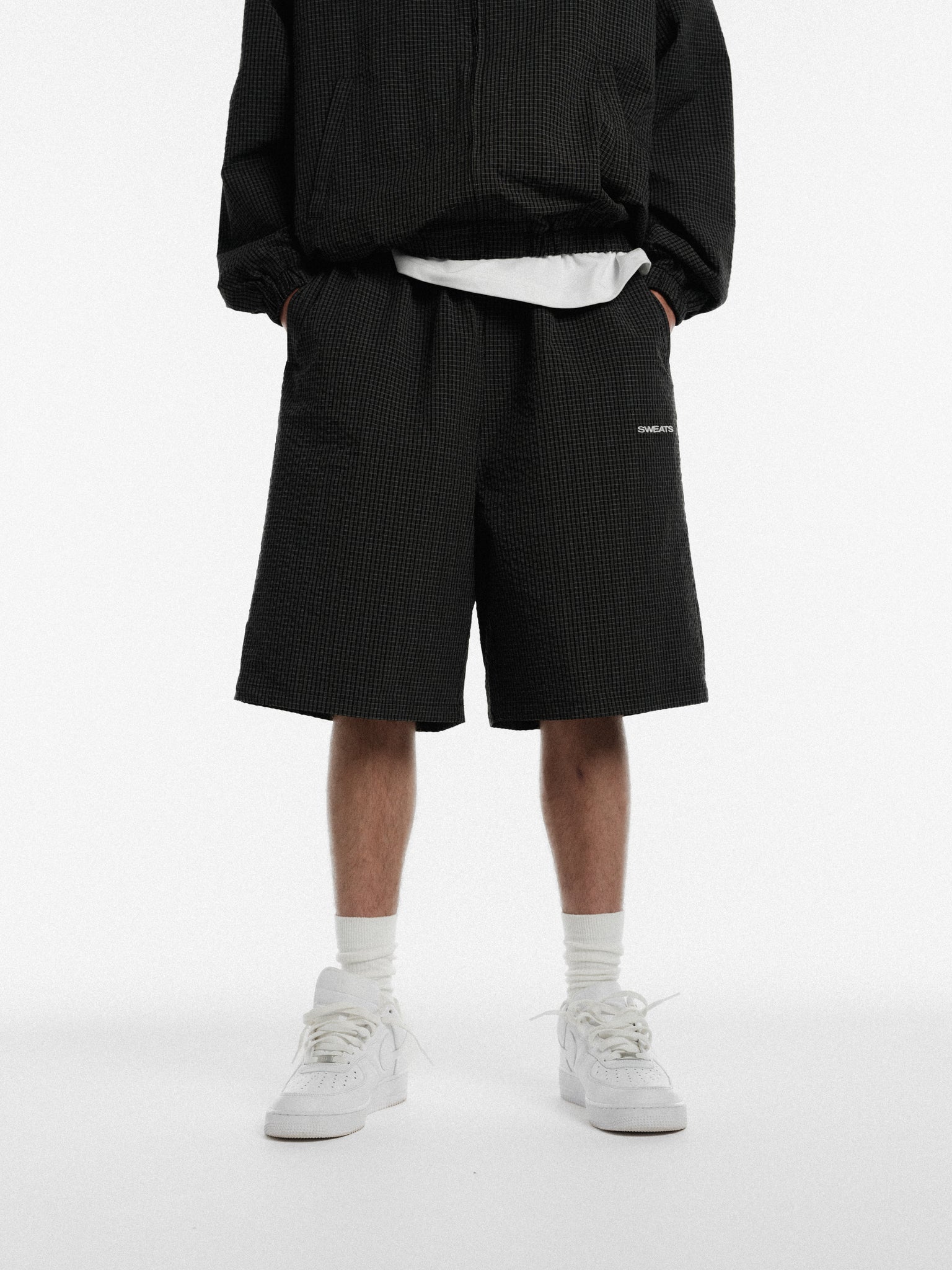 Black and white checked track shorts by Sweats UK, featuring a casual sporty design and comfortable fit.