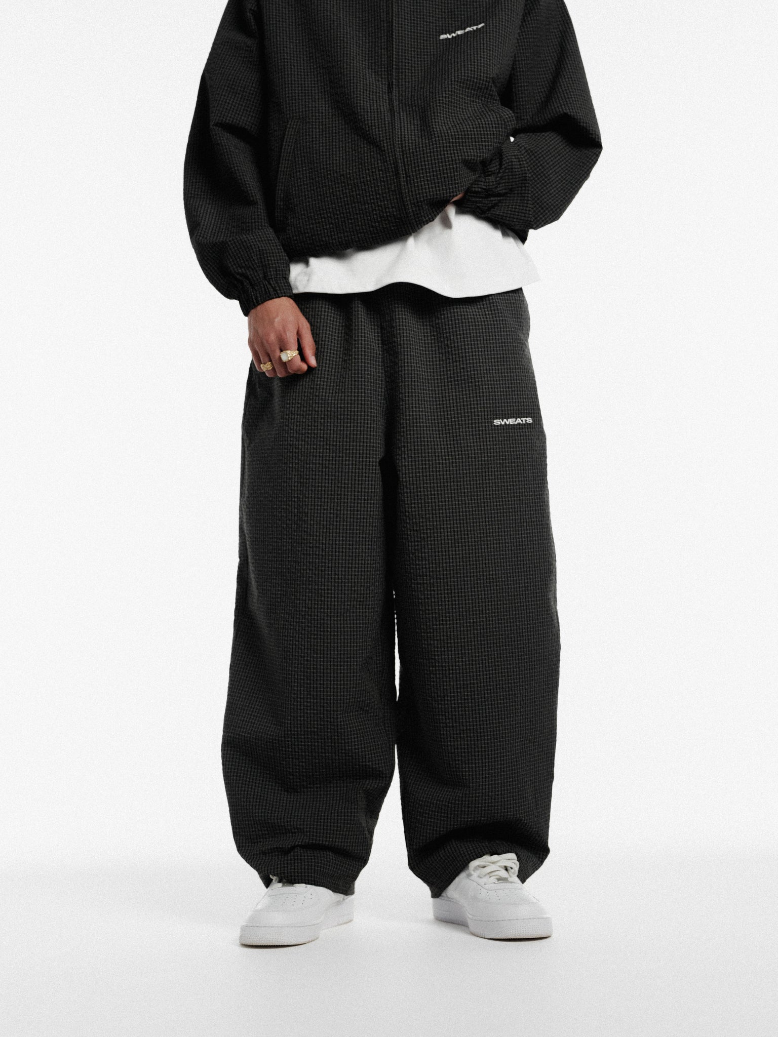 Black and white checkered track pants by Sweats UK, featuring a comfortable fit and stylish pattern for athletic or casual wear.