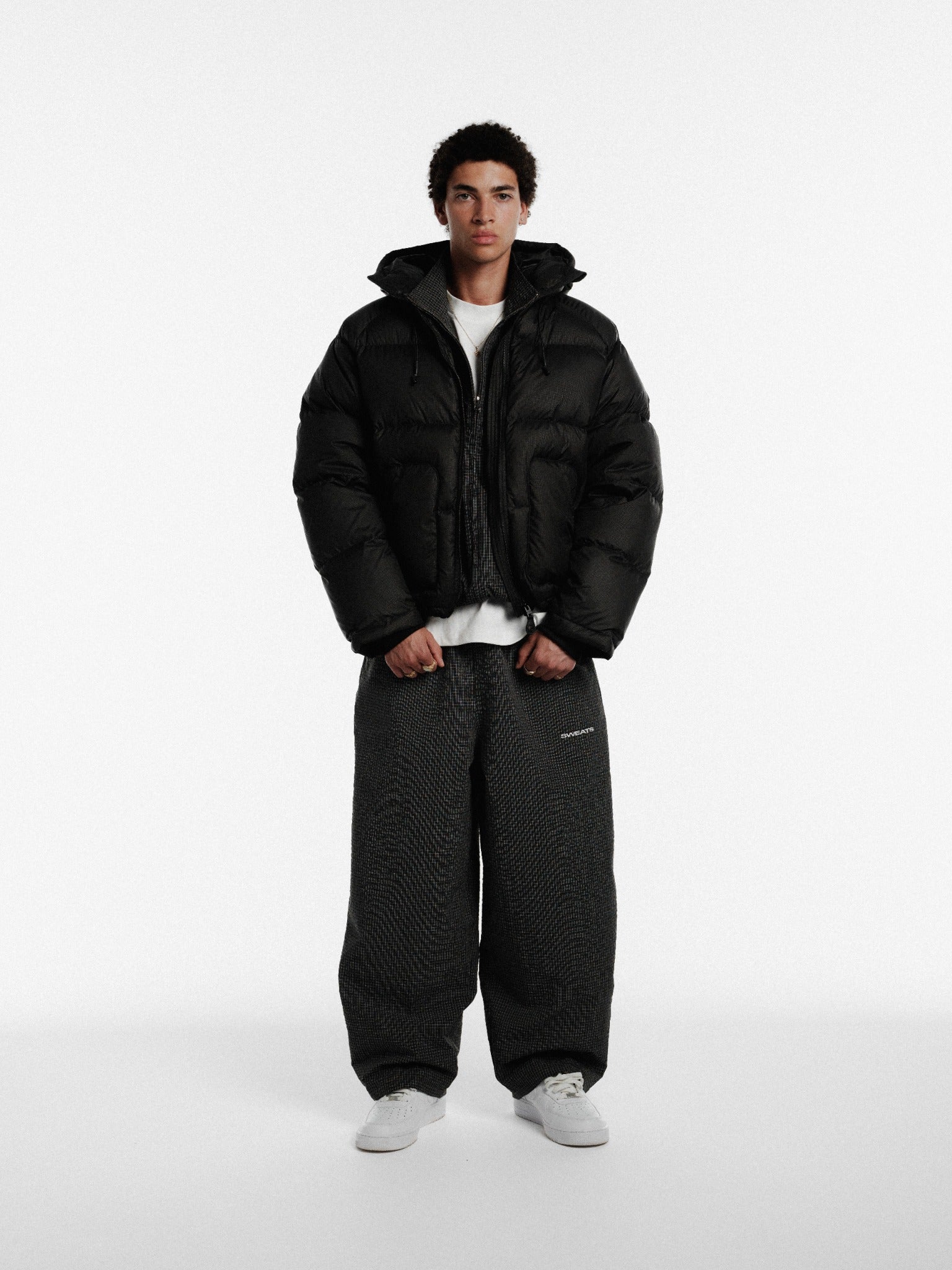 Black hooded puffer jacket by Sweats UK, insulated winter coat with a hood, stylish and warm outerwear for cold weather.