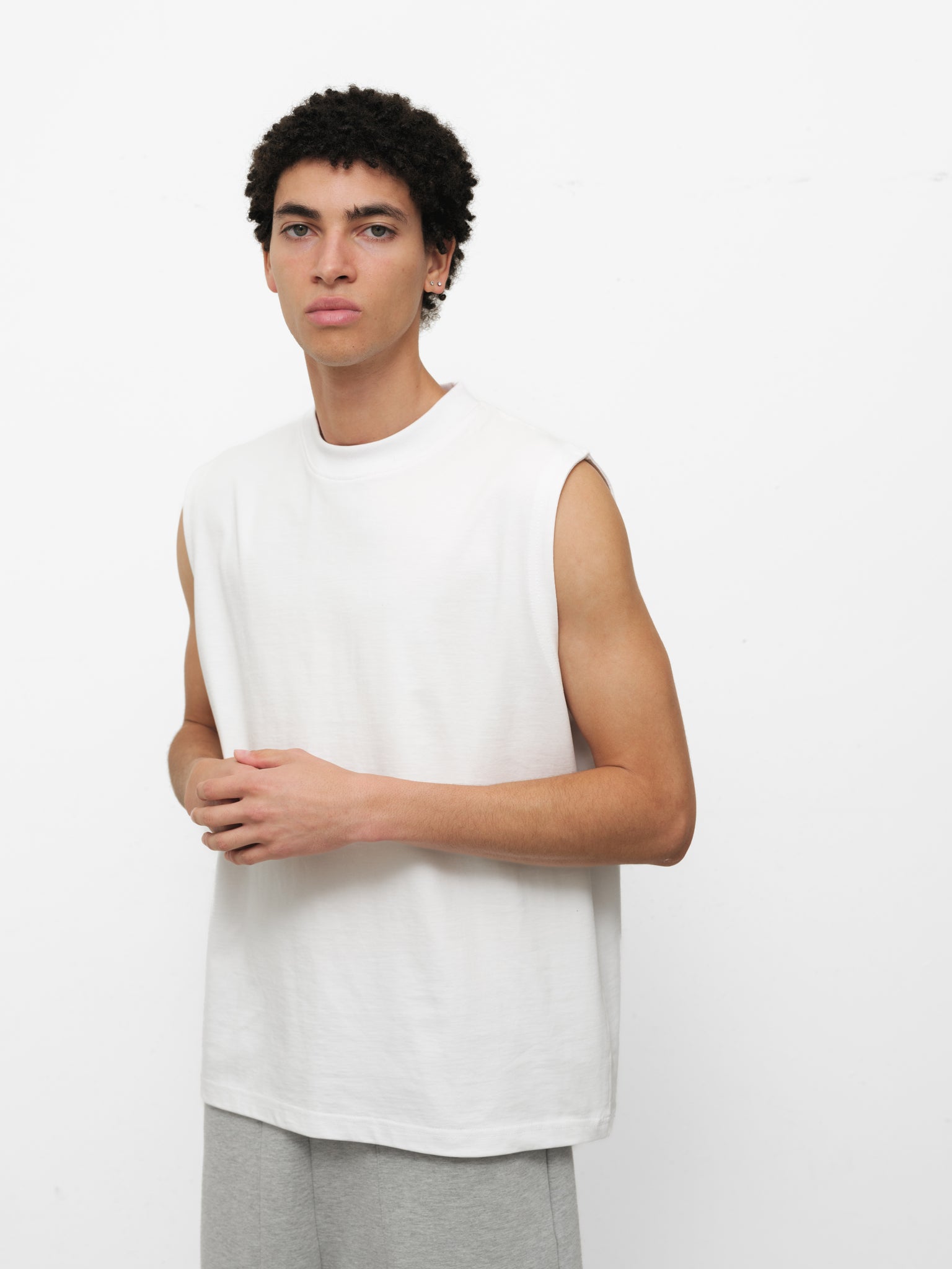 White muscle tee from Sweats UK featuring a sleeveless design and casual fit, displayed on a model.