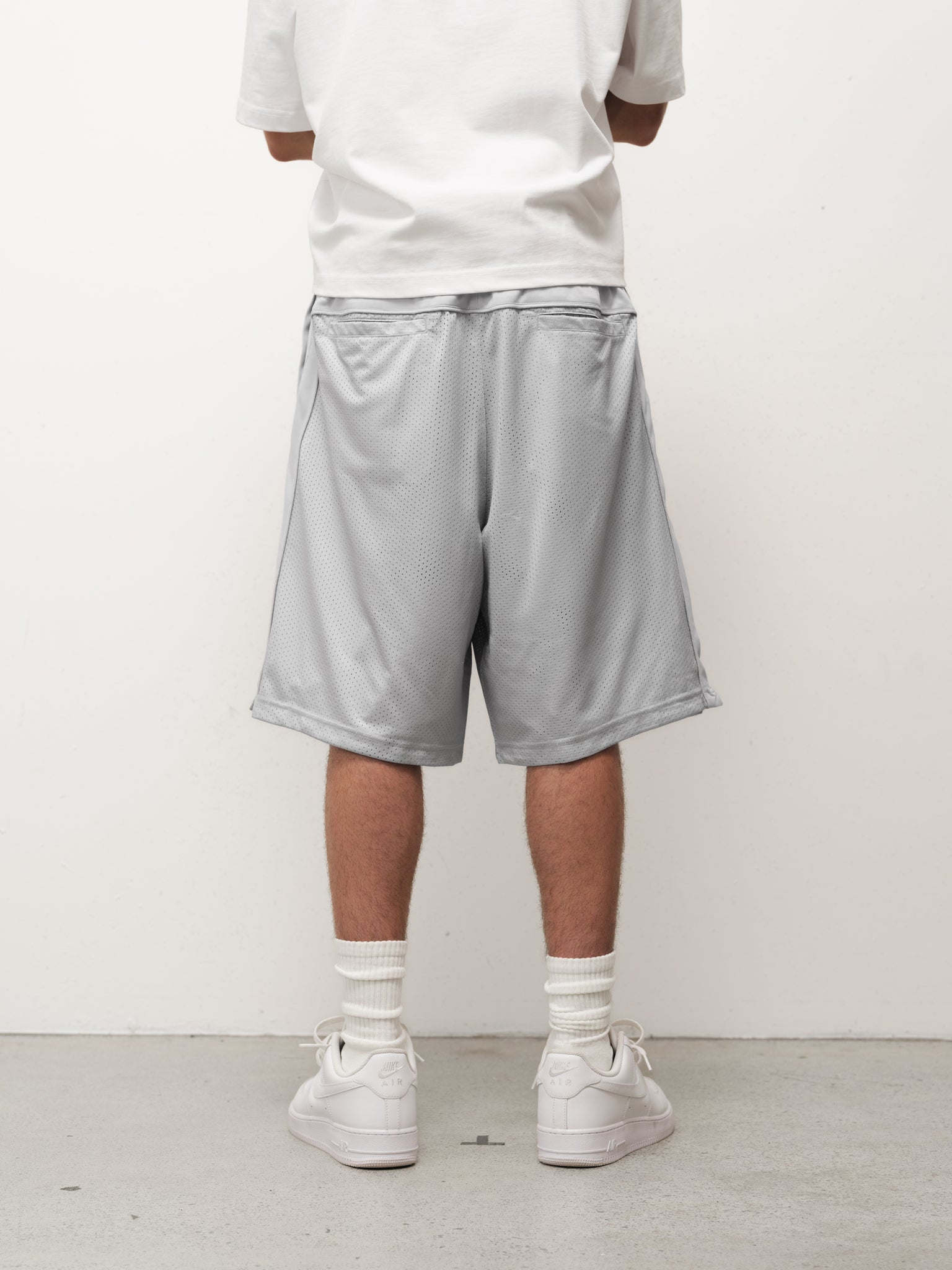Grey mesh shorts from Sweats UK, featuring breathable fabric and a relaxed fit, shown on a full stock shoot.