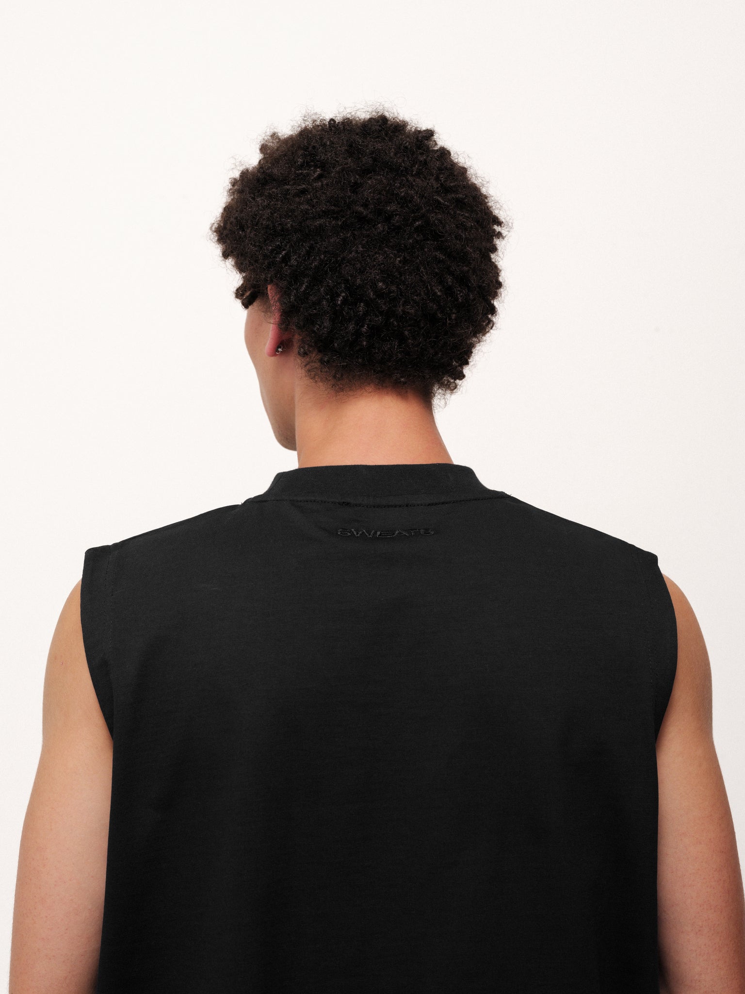 Black muscle tee from Sweats UK featuring a fitted sleeveless design and casual style, displayed on a plain background.