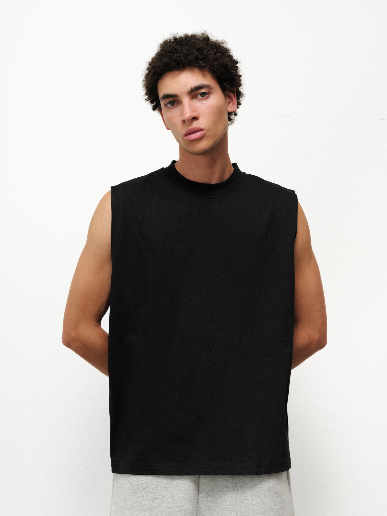 Black muscle tee by Sweats UK displayed on a model, showcasing a sleeveless, fitted athletic top ideal for workouts.