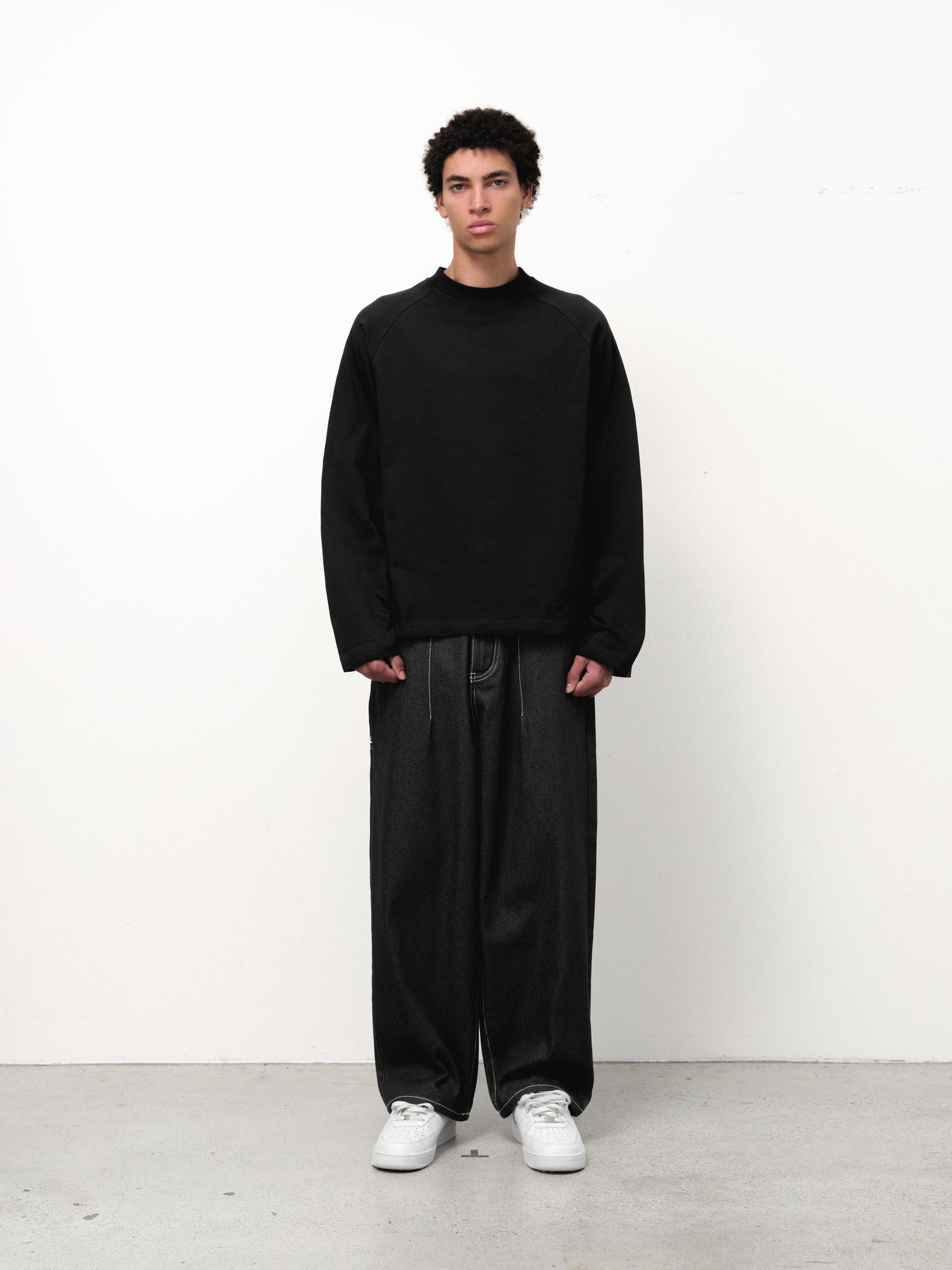 Black long sleeve T-shirt from Sweats UK displayed on a hanger, showcasing a casual, comfortable design.