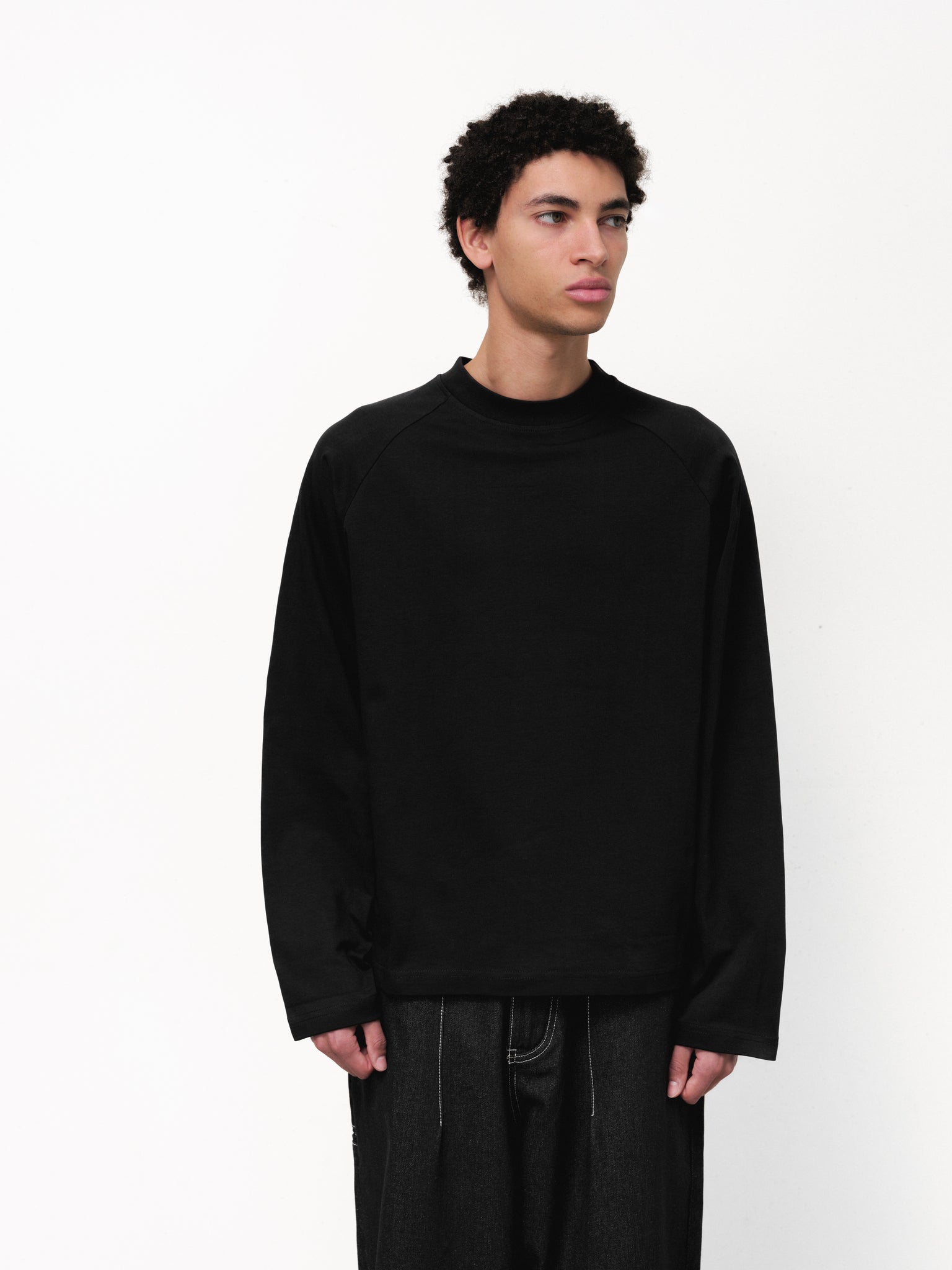 Black long sleeve T-shirt by Sweats UK displayed on a model, showcasing a casual fit and simple design.