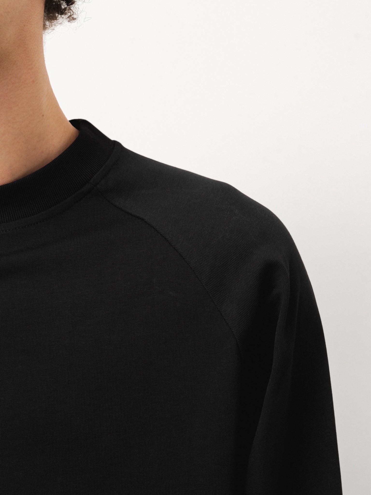 Black long sleeve T-shirt by Sweats UK displayed flat with visible crew neckline and smooth fabric.