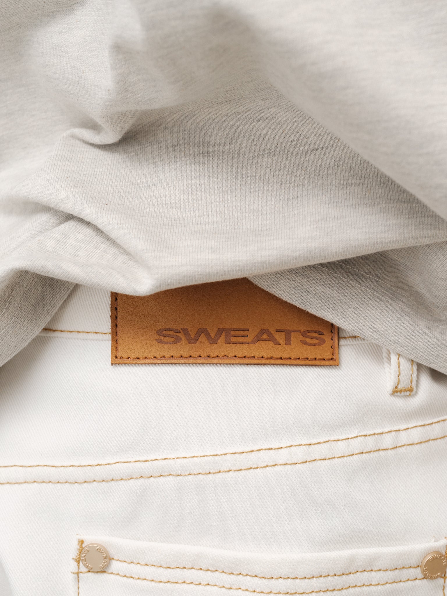 White denim baggy jeans by Sweats UK displayed on a model, showcasing a relaxed fit and casual streetwear style.