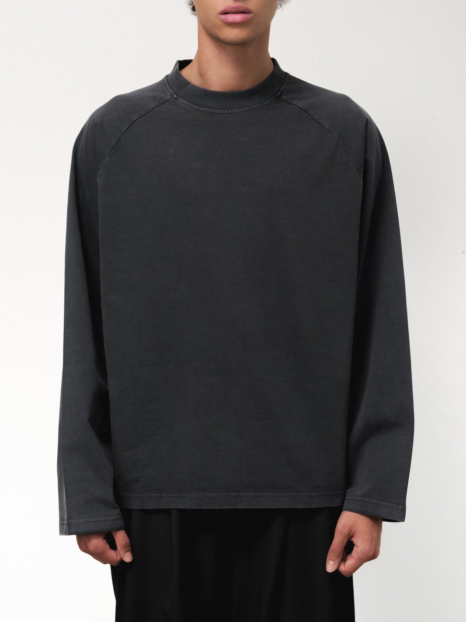 Washed black long sleeve T-shirt from Sweats UK displayed on a model, showcasing casual fit and fabric texture.