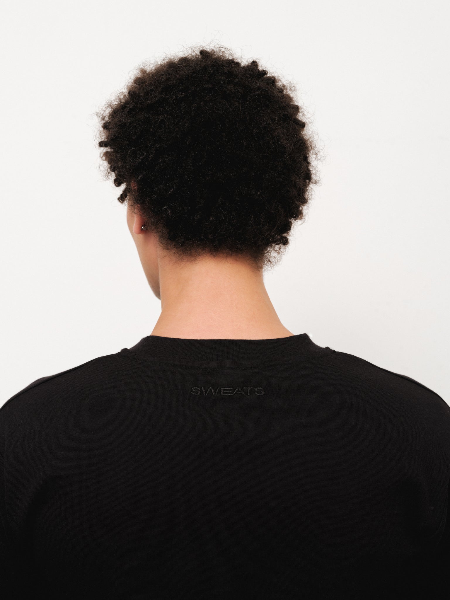 Black fitted T-shirt from Sweats UK displayed on a model, showcasing a sleek, casual fit and soft fabric.