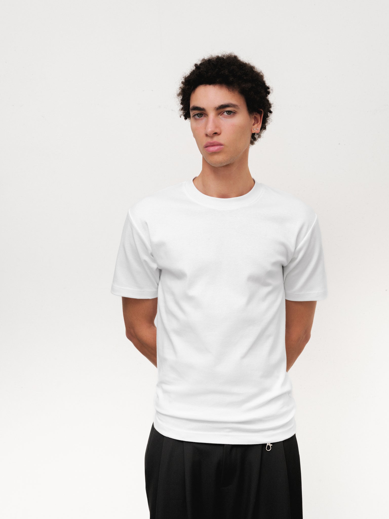 White fitted T-shirt by Sweats UK displayed on a mannequin, showcasing a casual, slim-fit design perfect for everyday wear.