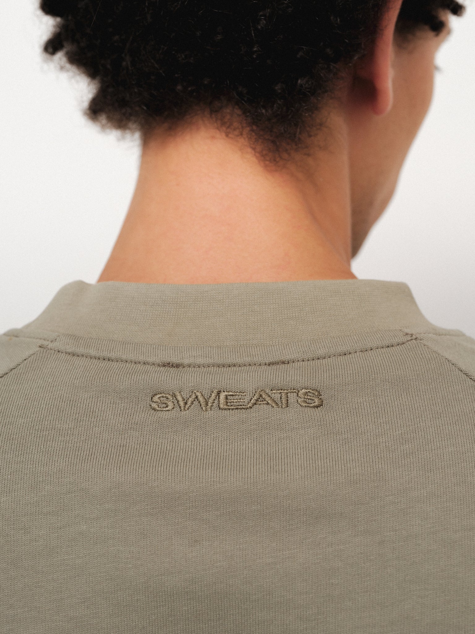 Long sleeve sage T-shirt from Sweats UK, shown on a hanger with a soft fabric texture and relaxed fit.