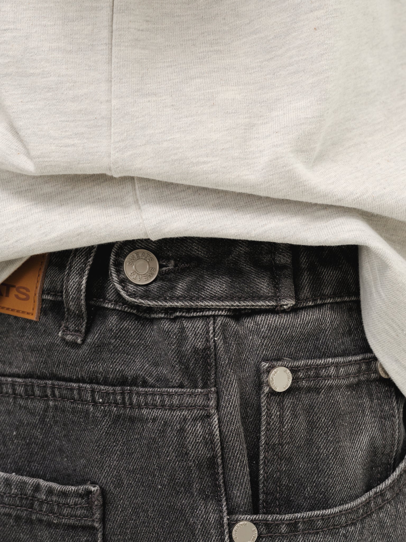 Washed black denim baggy jeans from Sweats UK, shown folded with a relaxed fit and classic five-pocket design.