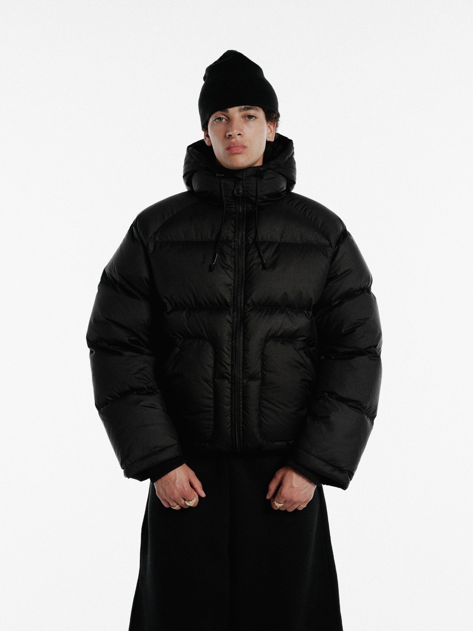 Black hooded puffer jacket by Sweats UK featuring a quilted design and front zipper, suitable for cold weather.