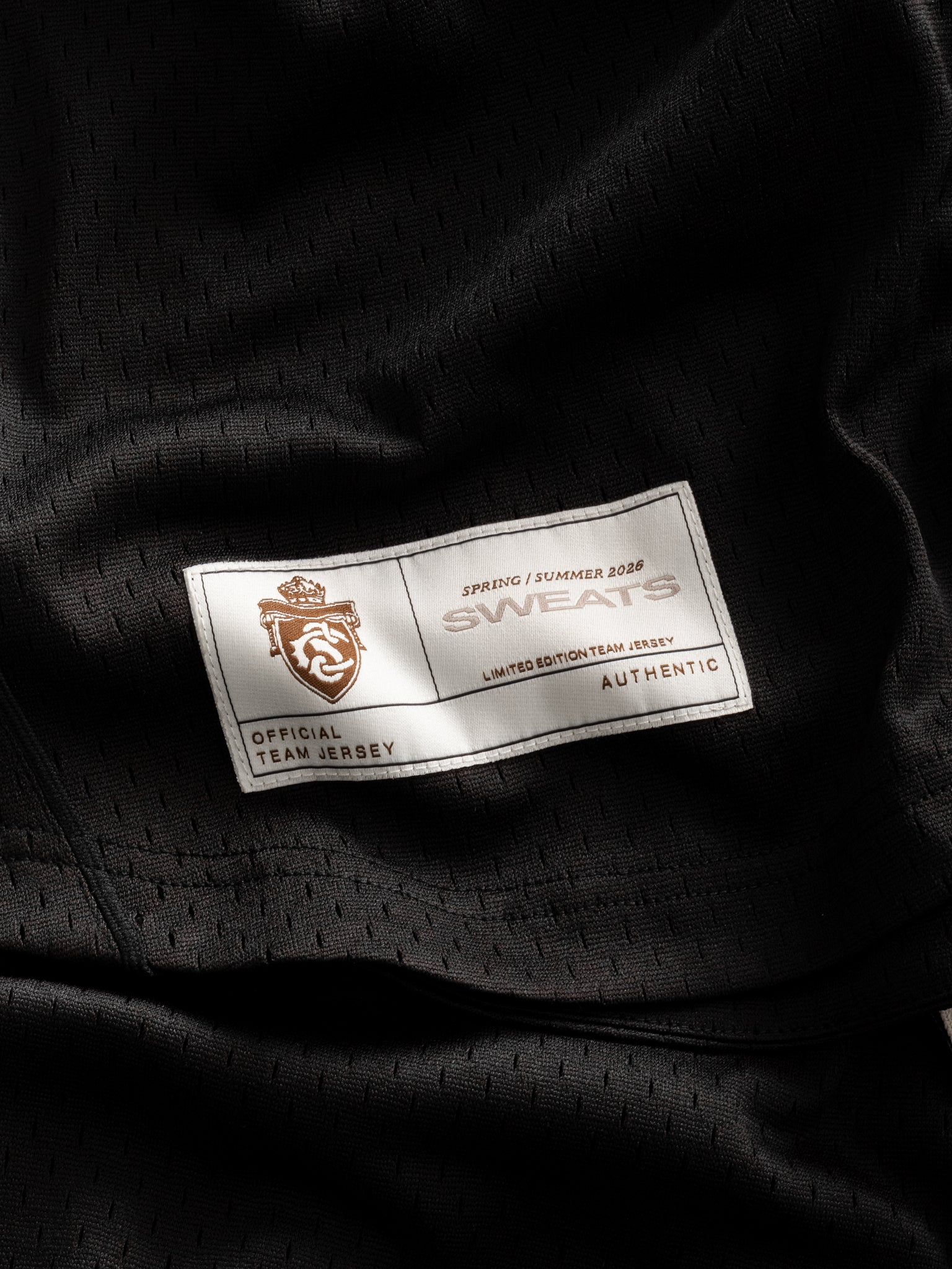 Black baseball jersey by Sweats UK displayed flat, showing front view with team logo and athletic design details.