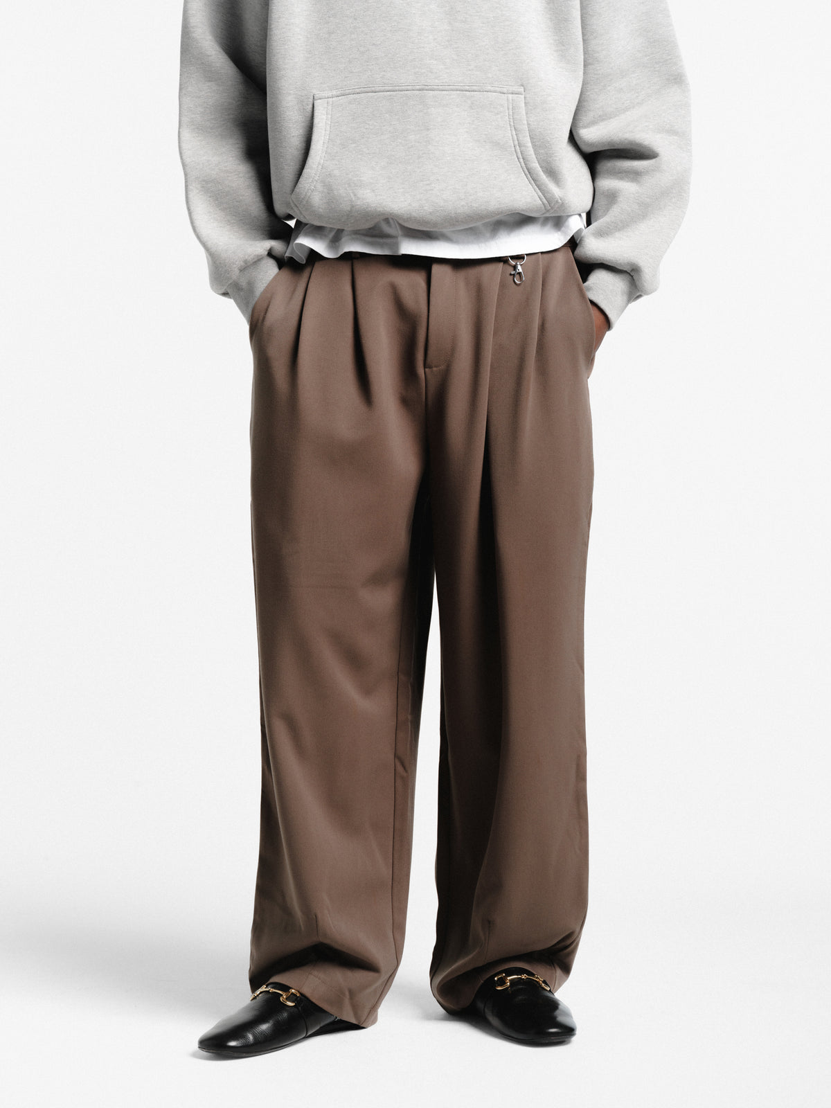 Brown pleated pants from Sweats UK, showcasing a stylish, tailored fit with crisp pleats and a classic design.