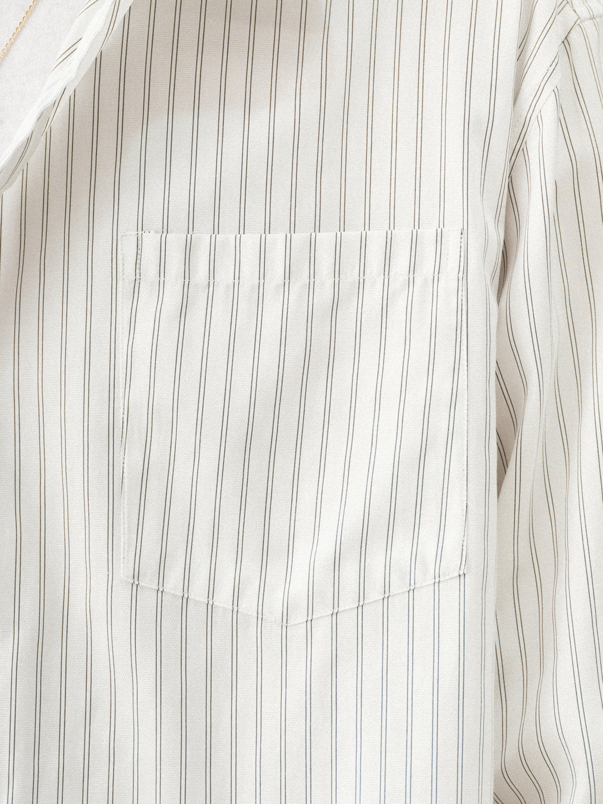 White striped button-up shirt by Sweats UK, featuring a classic collar and button front, displayed on a hanger.