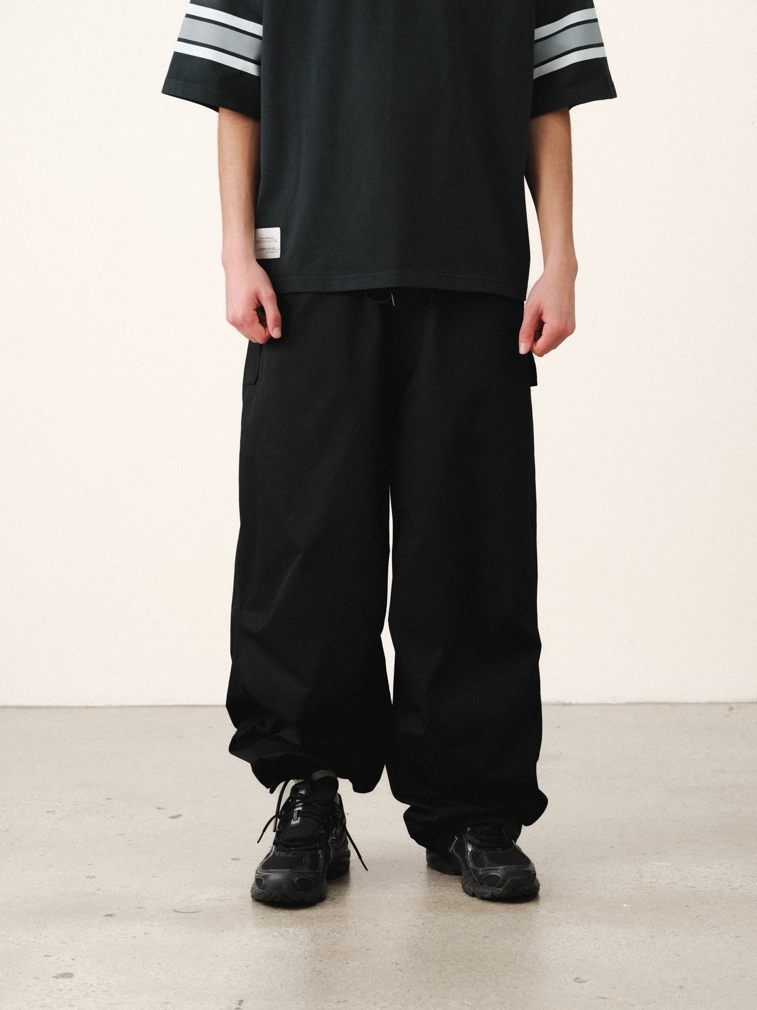 Black V3 Flight Pant by Sweats UK, featuring a relaxed fit and sporty design, shown in a casual outdoor setting.
