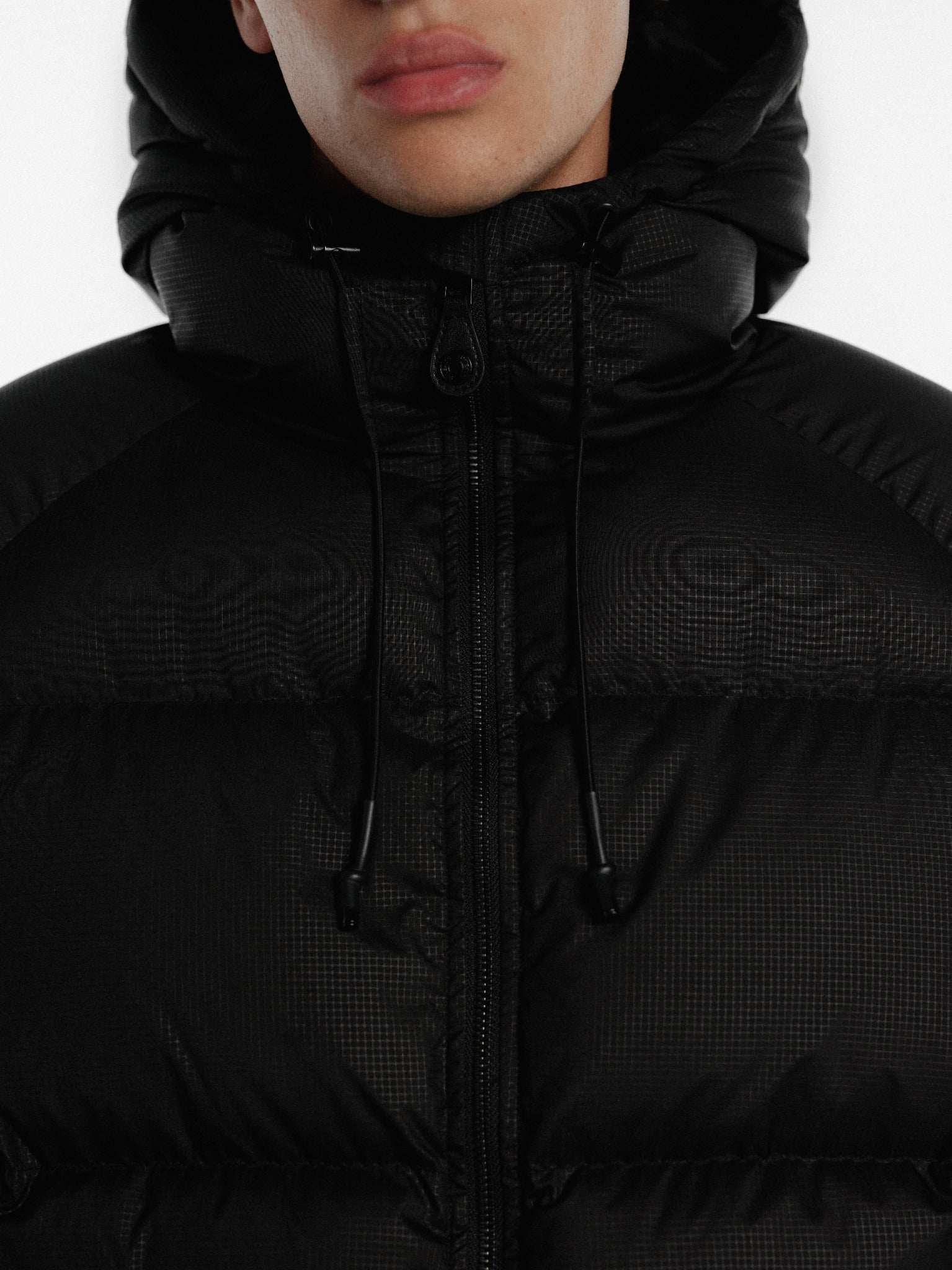 Black hooded puffer jacket by Sweats UK, shown with quilted design and front zipper for cold-weather wear.