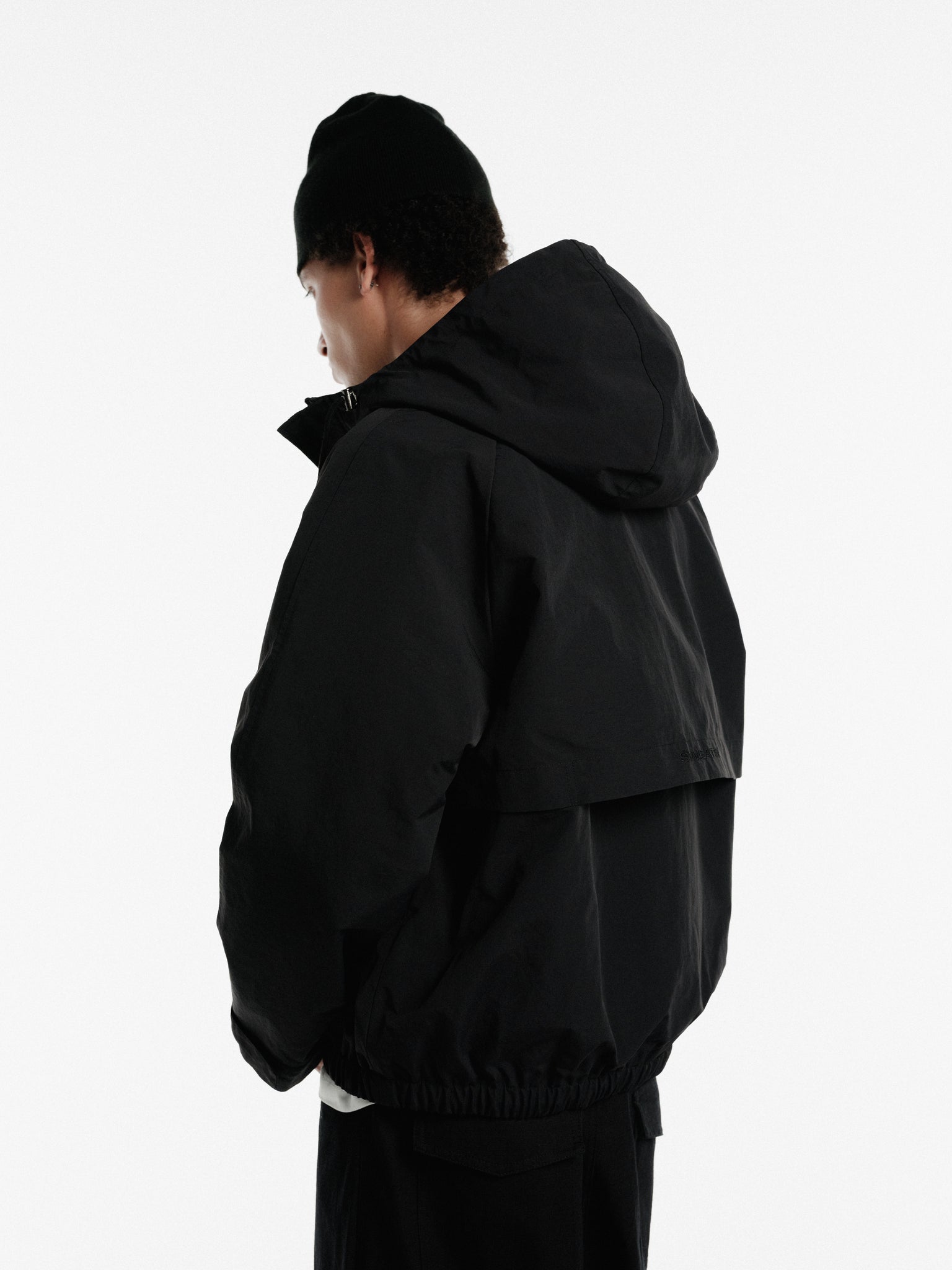 Black ARC Jacket by Sweats UK, shown on a hanger with front view, showcasing the sleek design and smooth fabric.