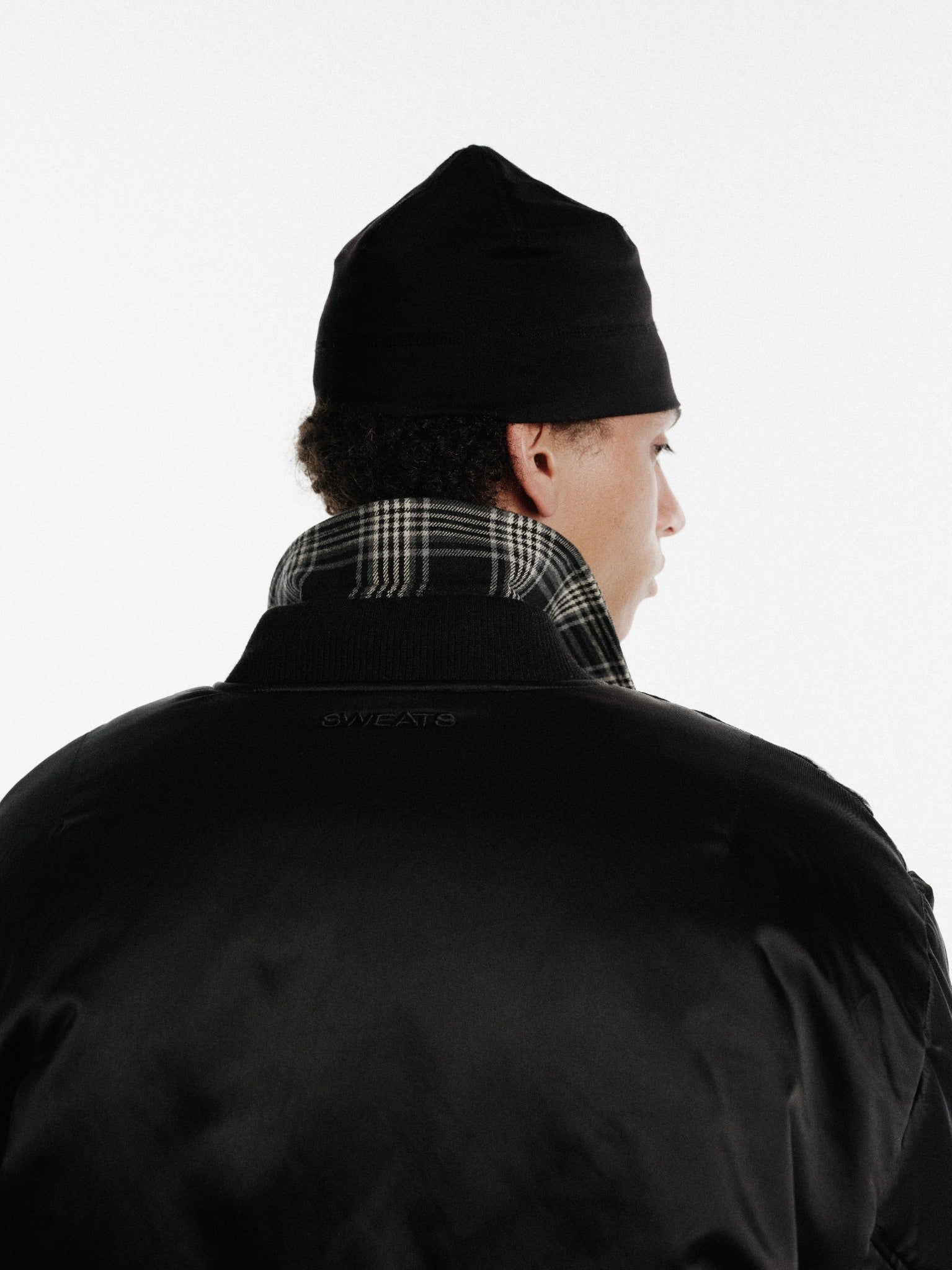 Black bomber jacket by Sweats UK featuring a classic design, shown hanging on a hanger with a smooth fabric finish.