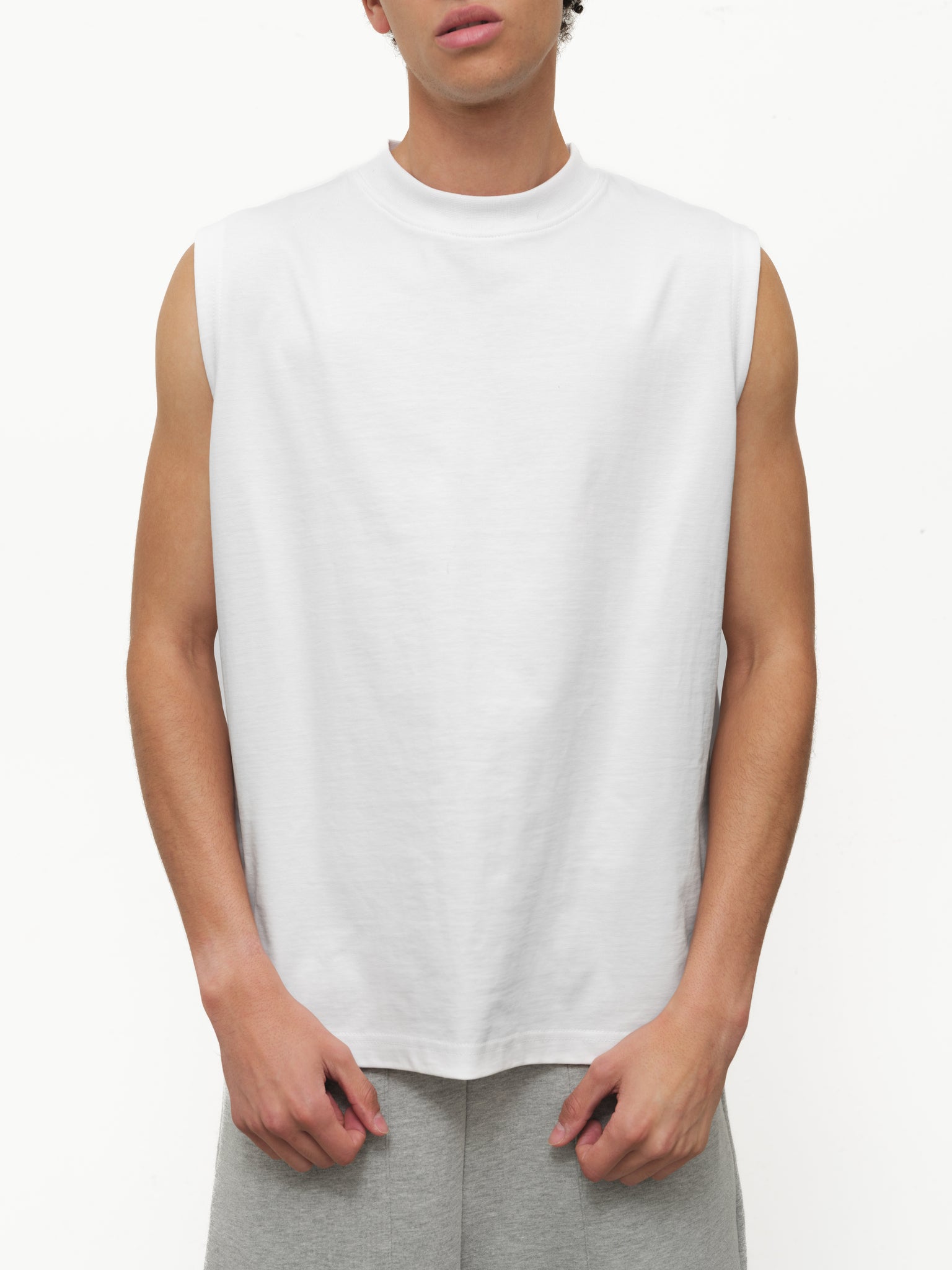 White muscle tee shirt from Sweats UK, featuring a sleeveless design and casual fit, displayed on a neutral background.