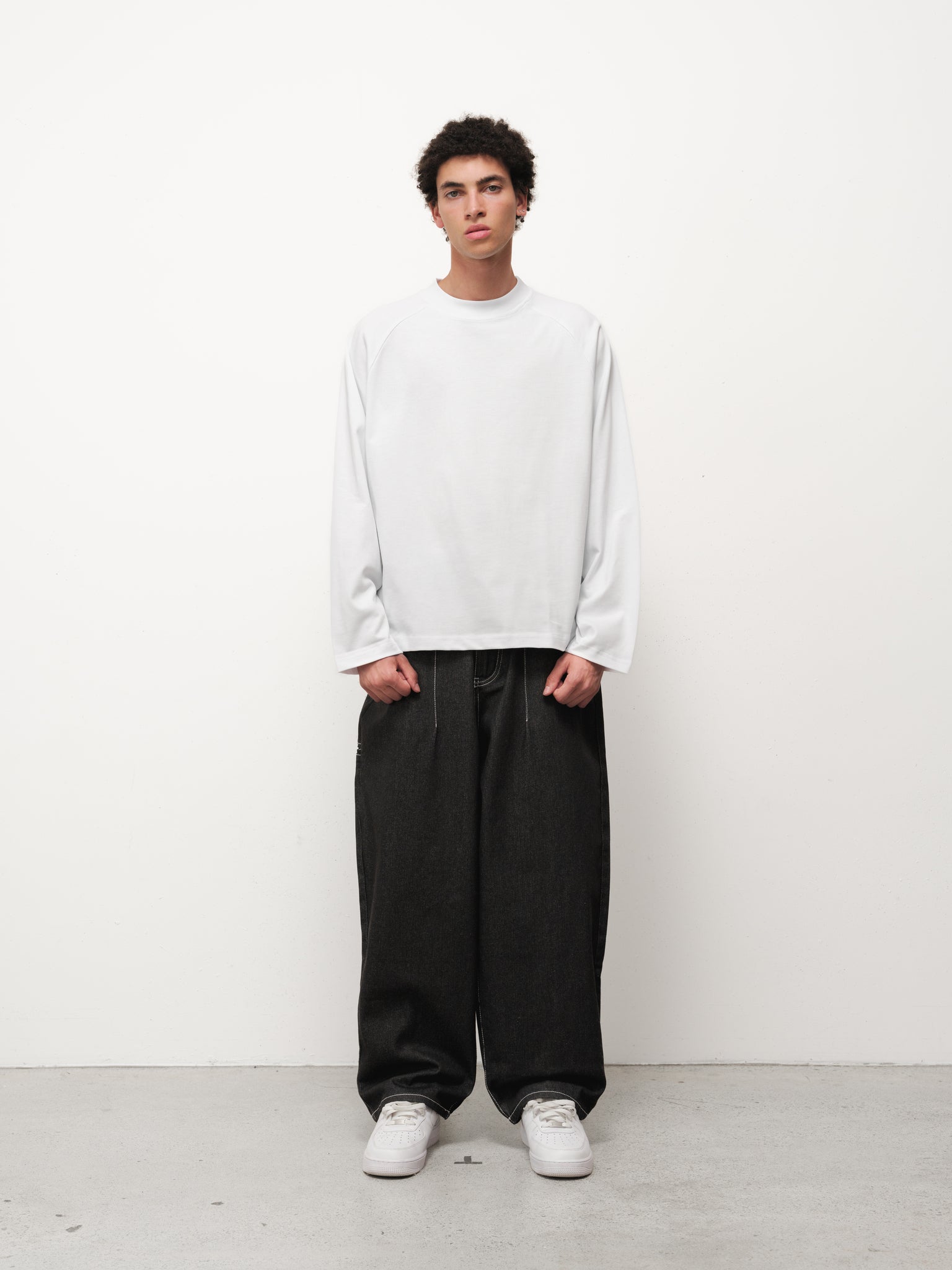 Black denim baggy jeans by Sweats UK displayed on a model, showcasing relaxed fit and classic five-pocket design.