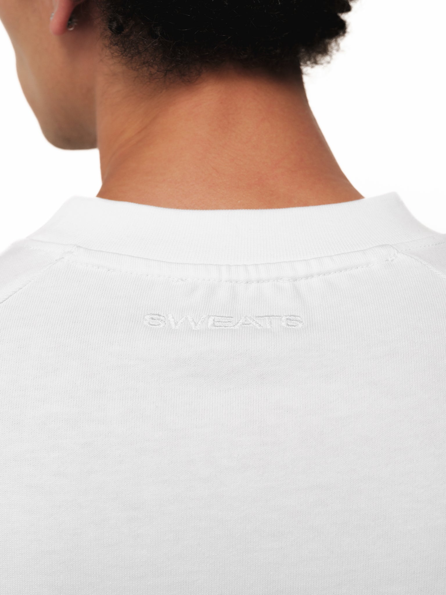 White long sleeve T-shirt from Sweats UK displayed on a model, featuring a simple, comfortable design with a crew neckline.