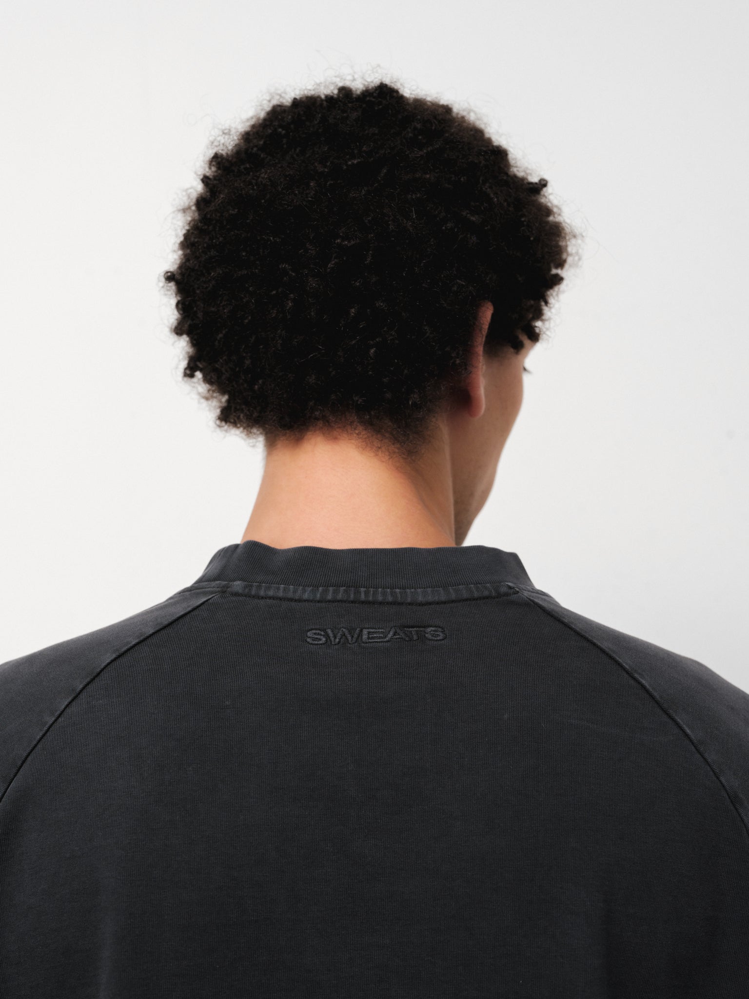Washed black long sleeve T-shirt by Sweats UK displayed on a model in a full stock shoot.