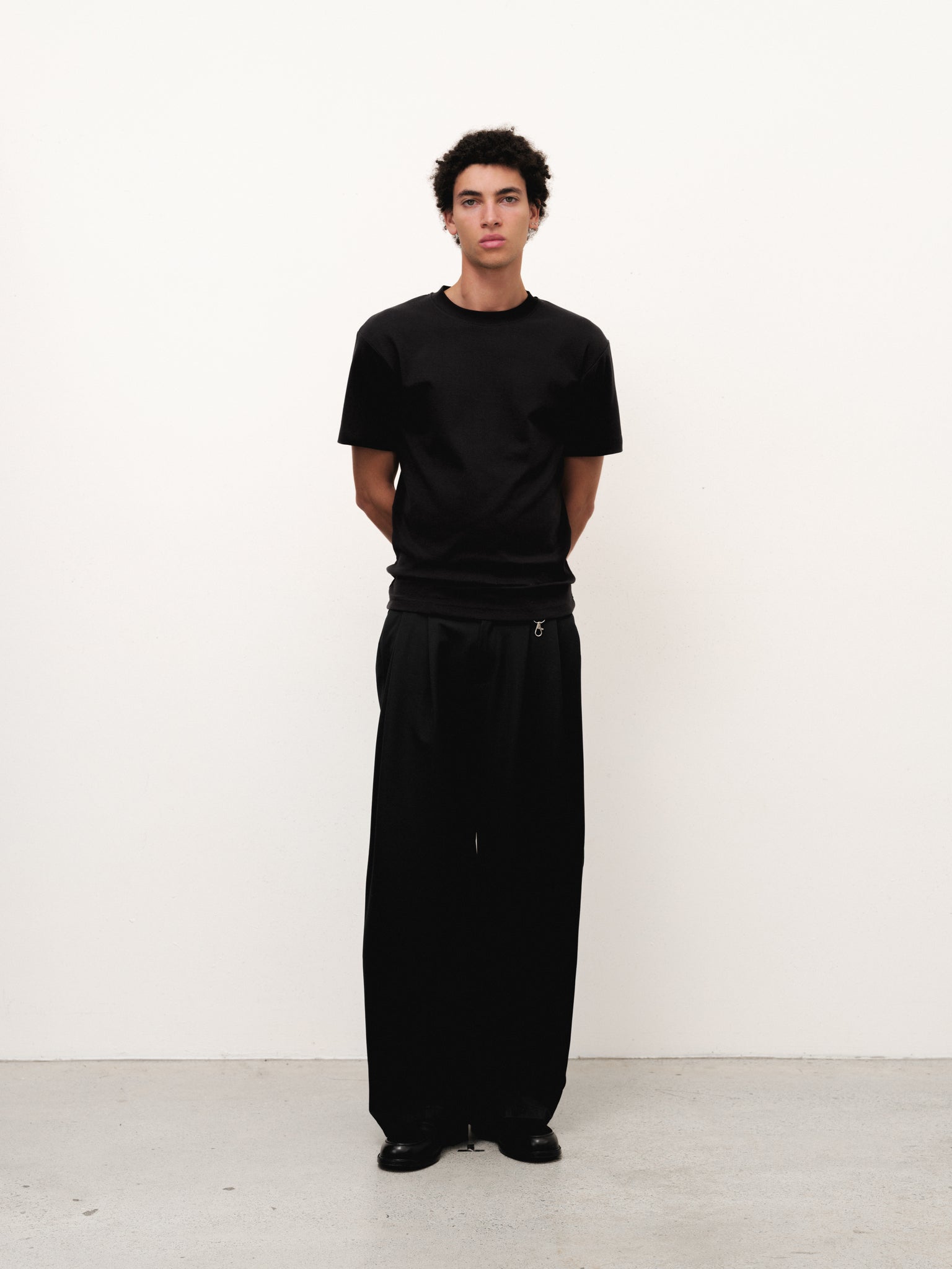Black fitted T-shirt from Sweats UK displayed on a model, highlighting its slim fit and casual style.