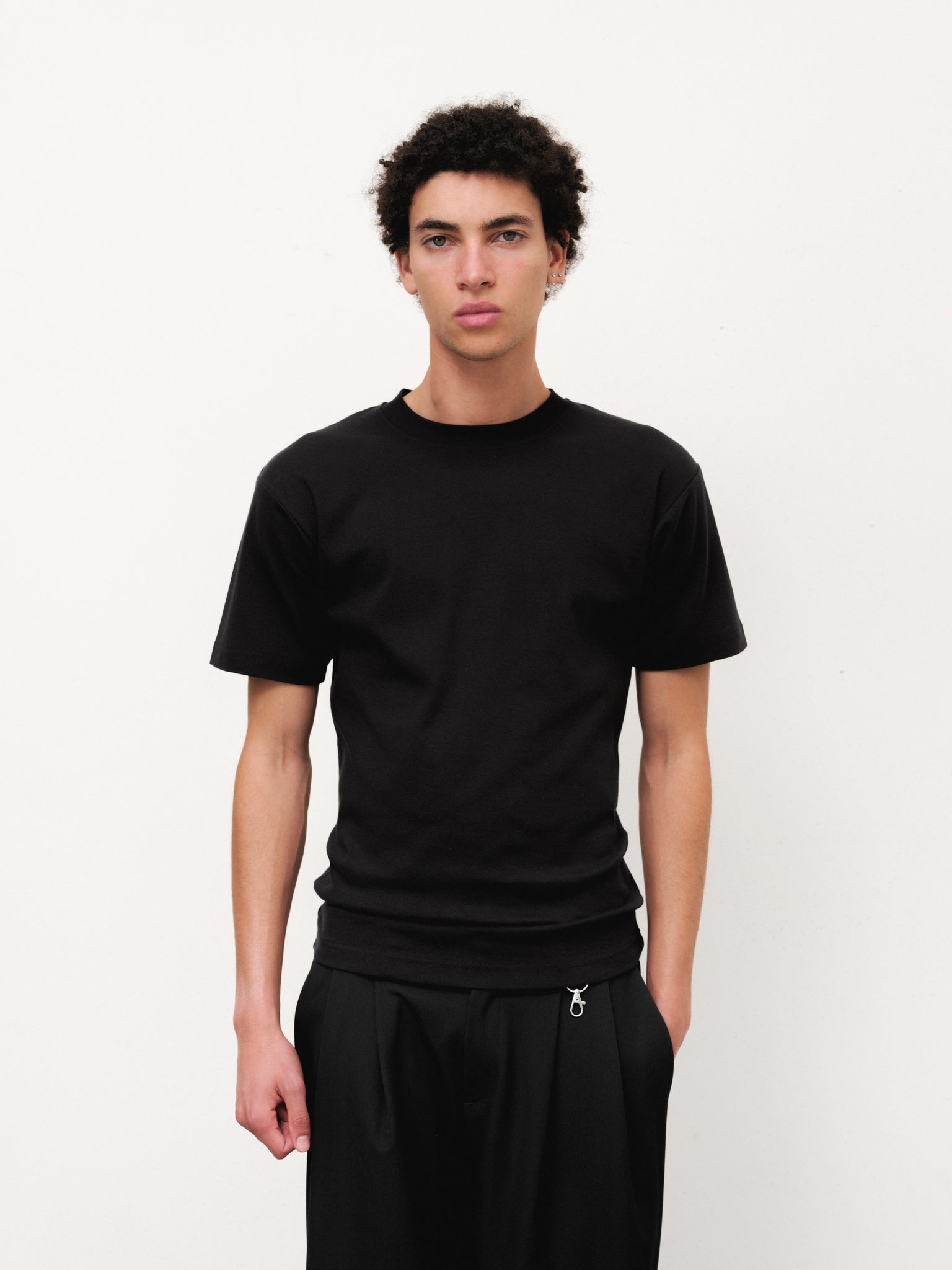 Black fitted T-shirt from Sweats UK, displayed on a hanger with a plain background, showcasing its slim fit design.