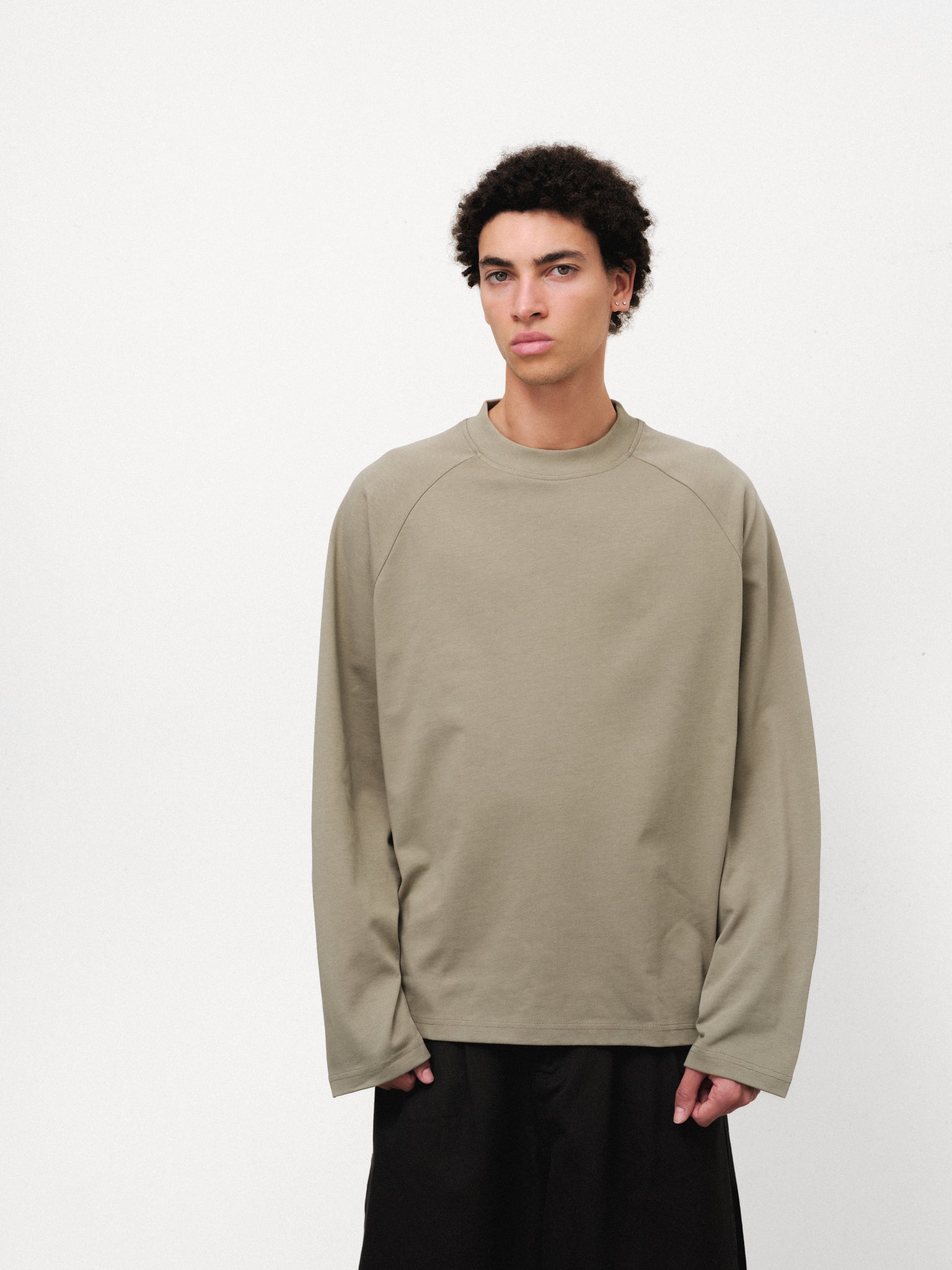 Long sleeve sage T-shirt by Sweats UK, shown on a model with a relaxed fit and casual style in a full-length shot.