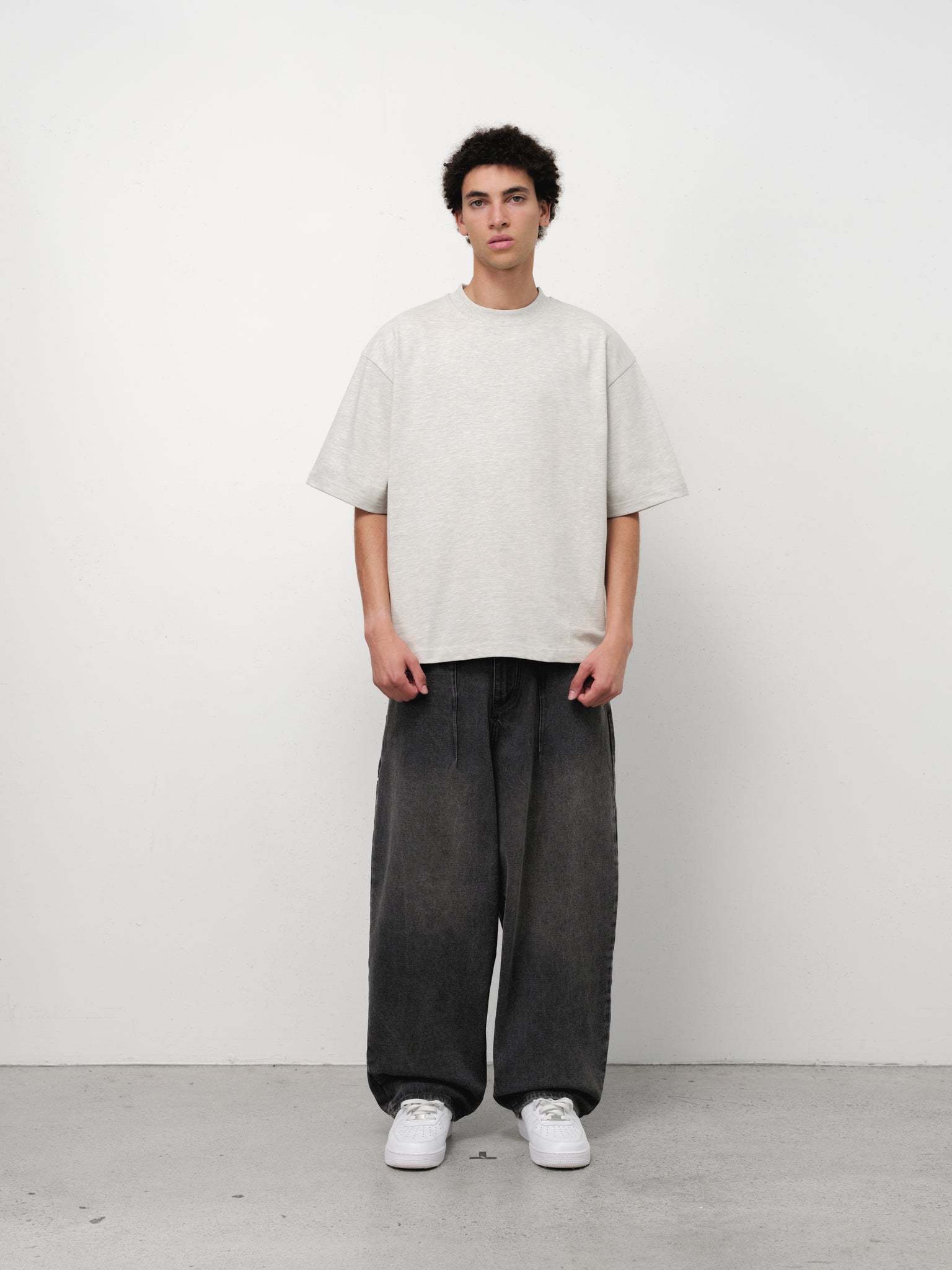 Washed black denim baggy jeans by Sweats UK, shown hanging with relaxed fit and distressed details on a neutral background.